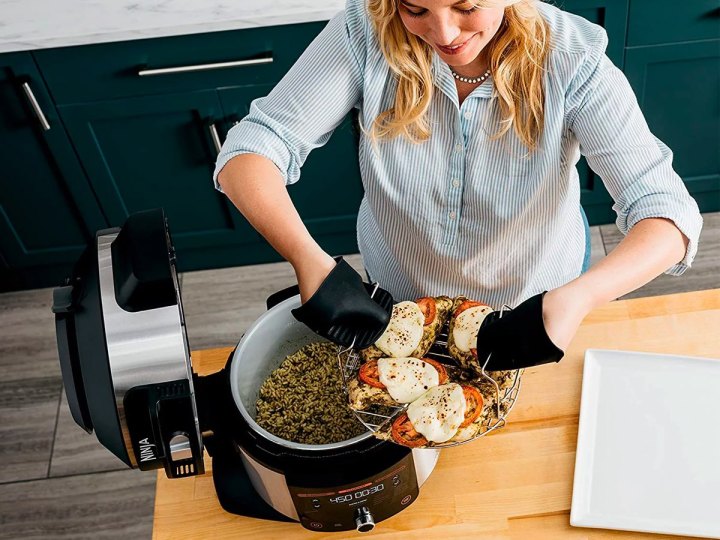 A woman loads the Ninja Foodi 6.5-quart pressure cooker with food.