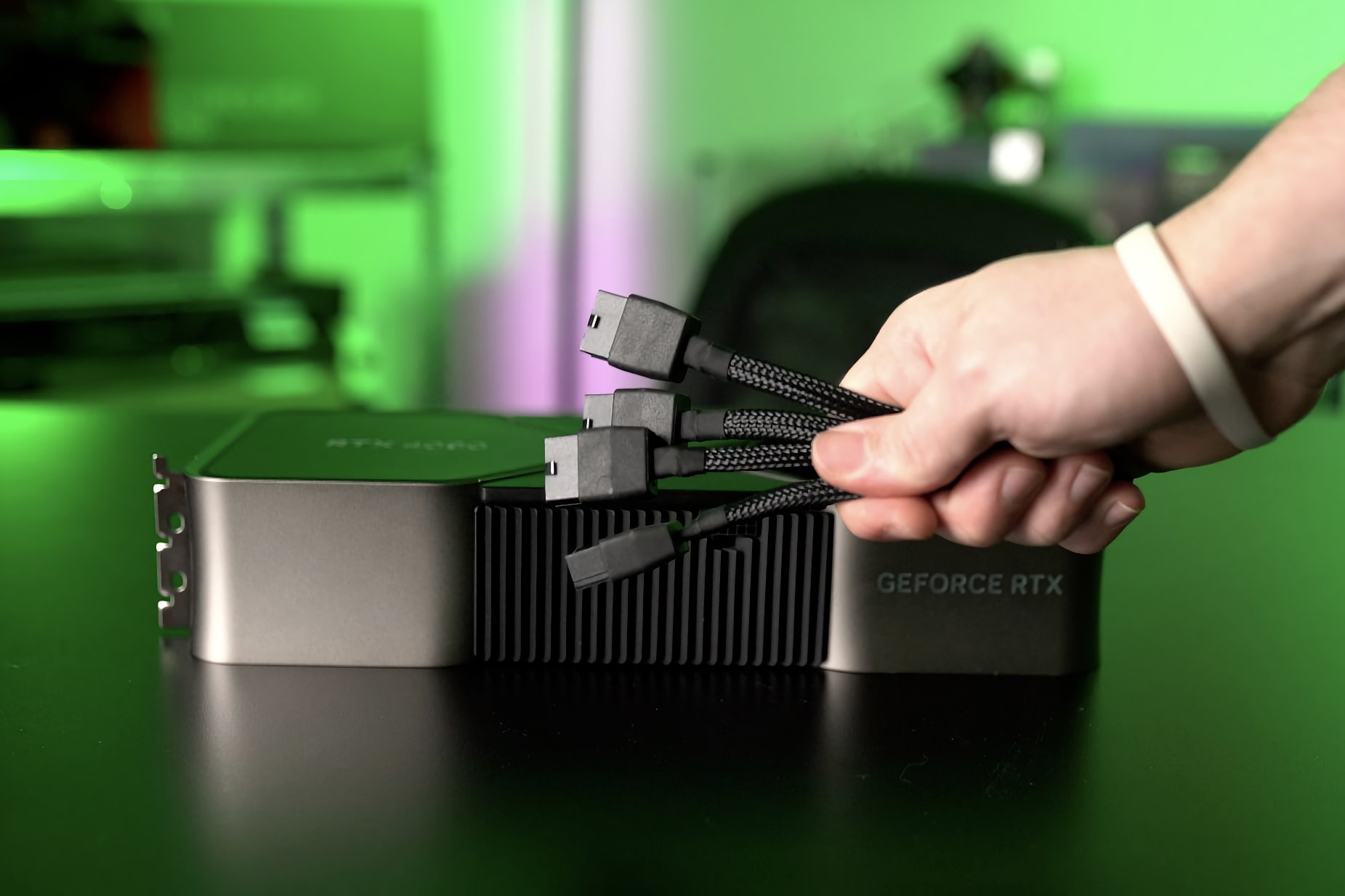 A Nvidia GeForce RTX 4090 é mostrada junto com uma mão segurando o adaptador do cabo de alimentação.