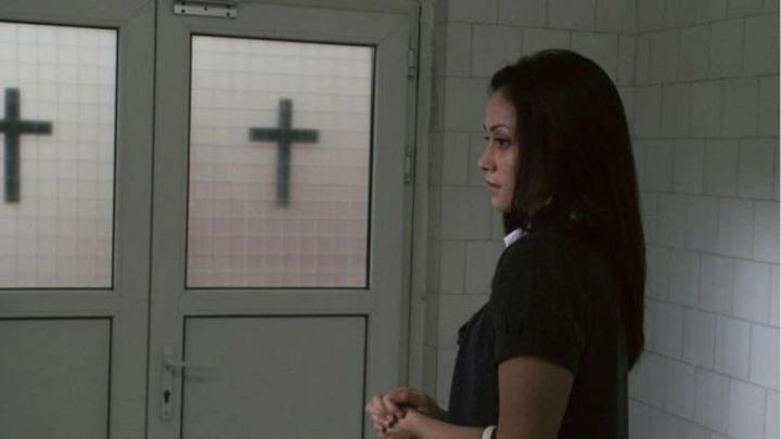 A young woman standing in front of two doors in the 2012 film The Devil Inside.
