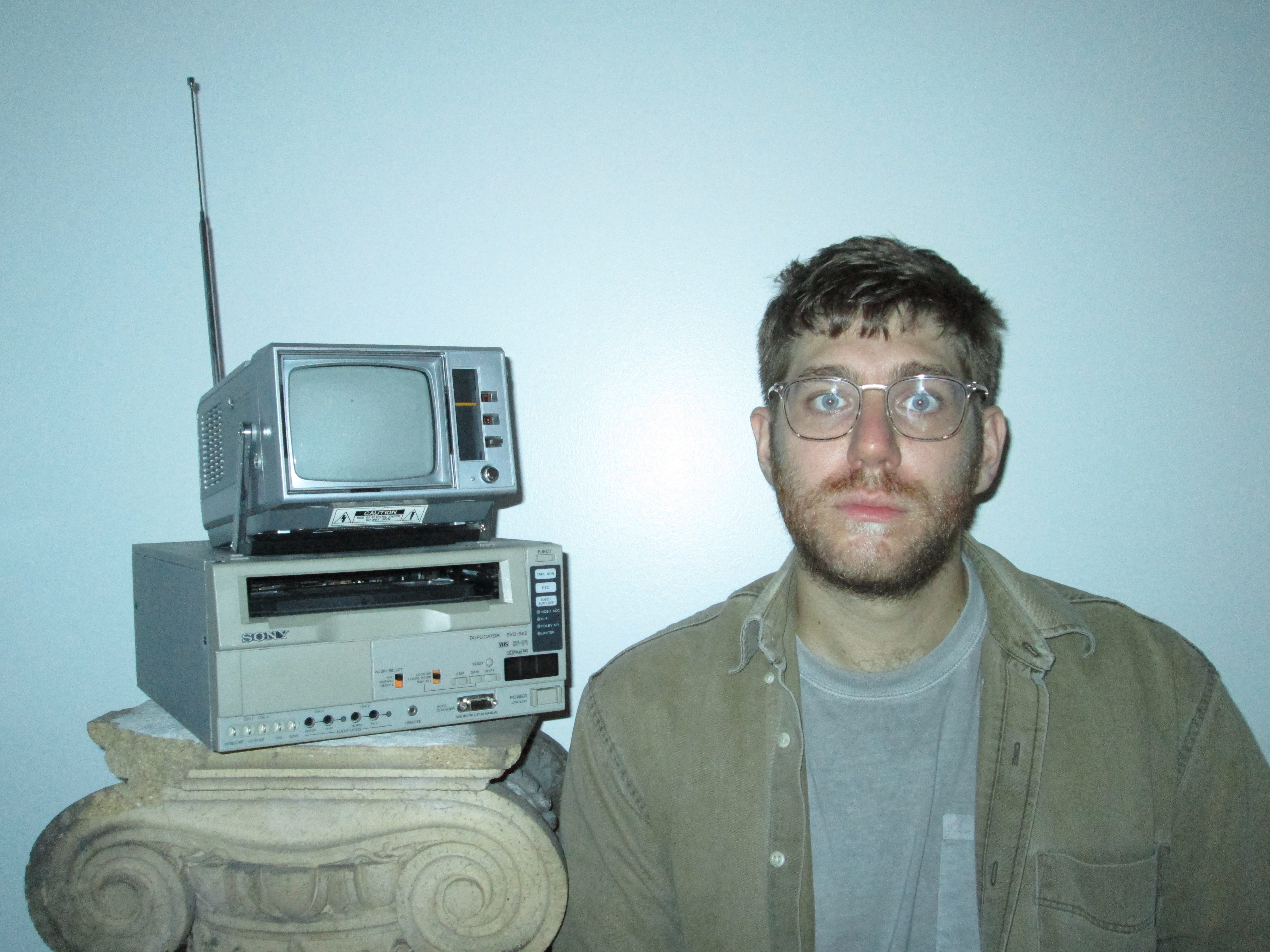 Alex Phillips posiert vor einem alten Fernseher.