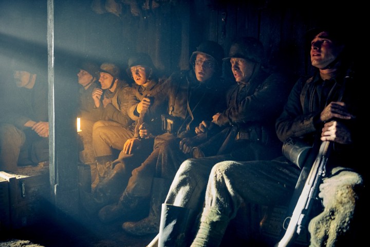 Soldiers sit in a trench in All Quiet on the Western Front.