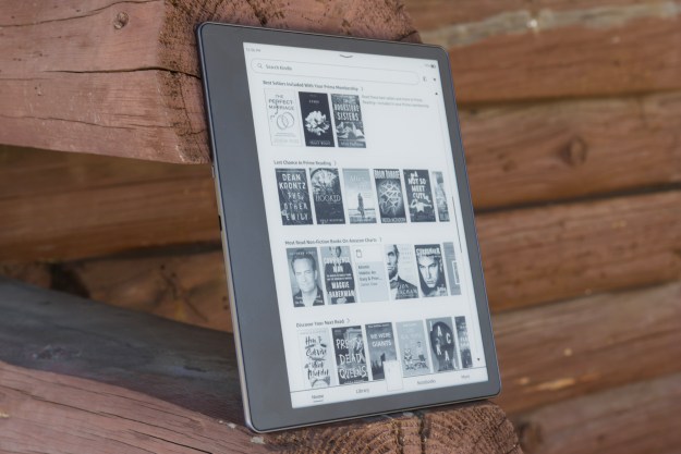 Amazon Kindle Scribe leaning up against a log cabin.
