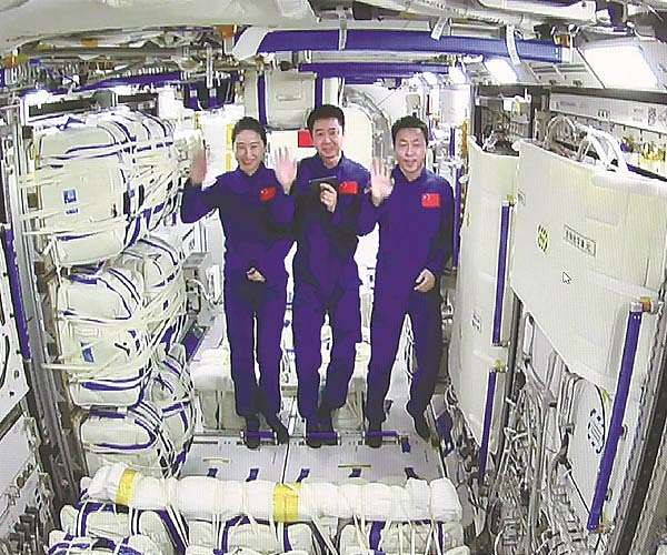 Shenzhou-14 astronauts Chen Dong (C), Liu Yang (L) and Cai Xuzhe waving inside the Mengtian lab module. 