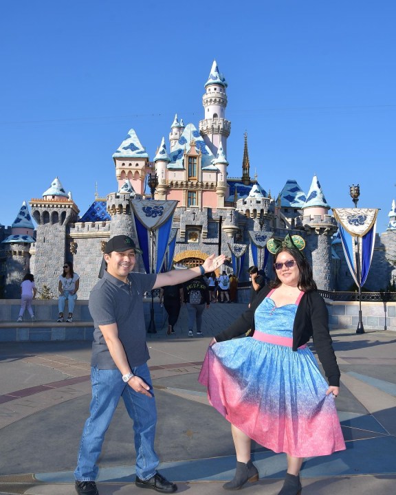 Christine and her husband pose in front of the Disneyland castle.