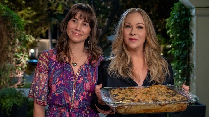 Linda Cardellini and Christina Applegate at a doorway with baked goods in a scene from Dead to Me.