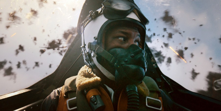 A Black pilot played by Jonathan Majors looks at missiles exploding around him in Devotion.
