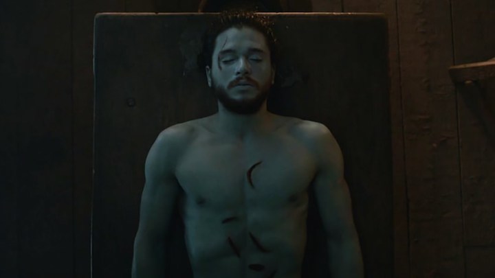 Jon Snow lying on a table, bloody and white in a scene from Game of Thrones.