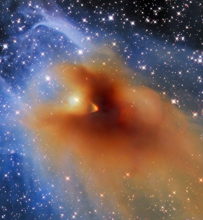 A small, dense cloud of gas and dust called CB 130-3 blots out the center of this image from the NASA/ESA Hubble Space Telescope. CB 130-3 is an object known as a dense core, a compact agglomeration of gas and dust. This particular dense core is in the constellation Serpens and seems to billow across a field of background stars.