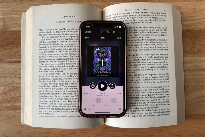 Aplikacija Libby, prikazana na iPhonu 12, ki leži na vrhu odprte knjige.