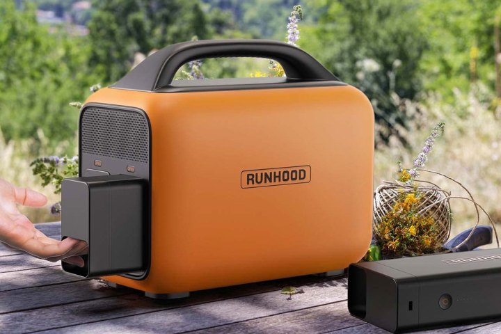 The Runhood Rallye 600 power station set on a table outdoors having a battery pack removed.
