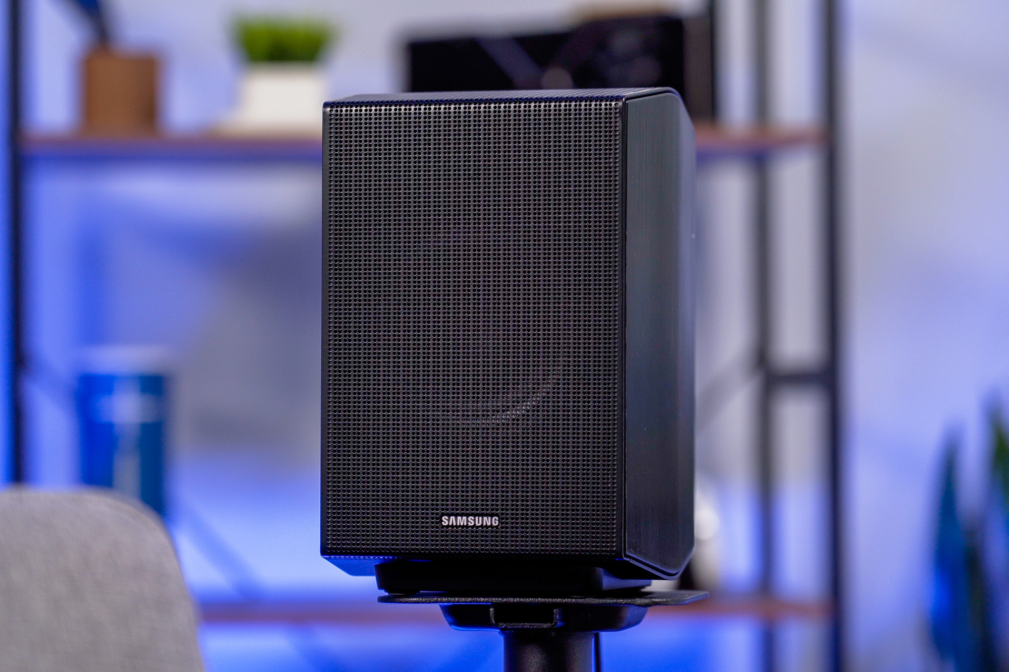 A Samsung Q990B soundbar system's surround speaker sitting atop a speaker stand