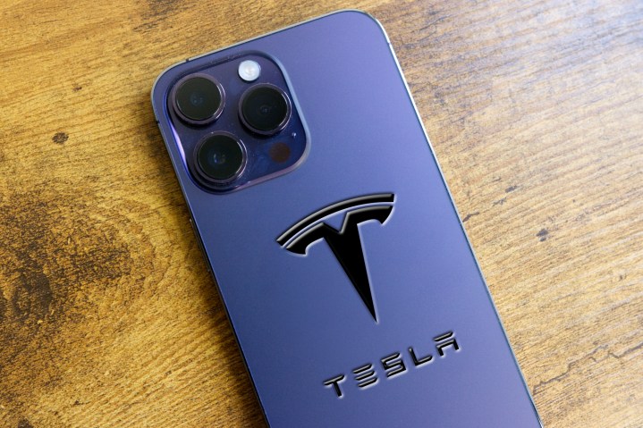 Arkasında Photoshop ile Tesla logosu bulunan bir iPhone 14 Pro.