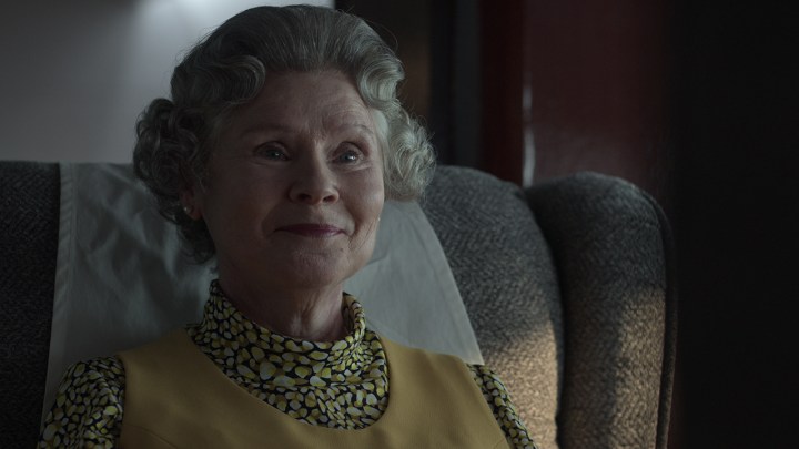 The Queen from The Crown season 5, sitting and smiling.