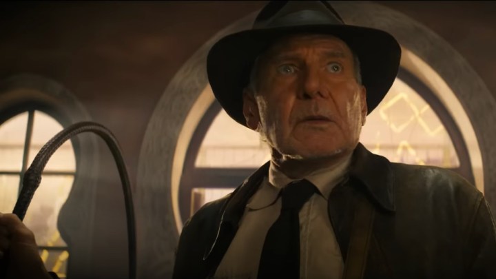 Harrison Ford como Indiana Jones segura um chicote inteiro parecendo confuso em Indiana Jones e o Dial of Destiny.