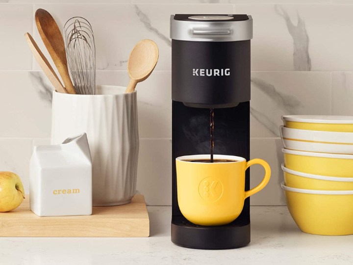 A cafeteira Keurig K-Mini no balcão da cozinha com xícaras e tigelas cor de limão.