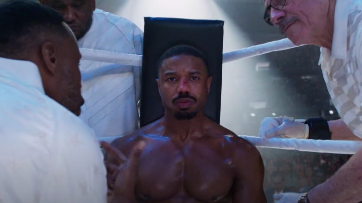Michael B. Jordan sits on a stool in a boxing ring in Creed III.