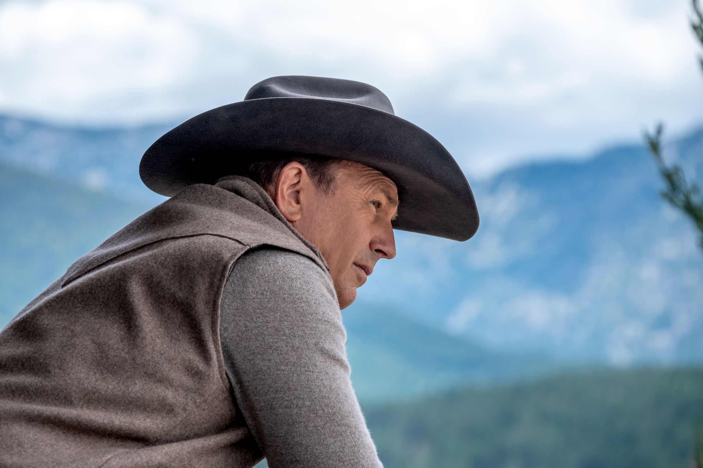 Kevin Costner se inclina sobre uma cerca em Yellowstone.