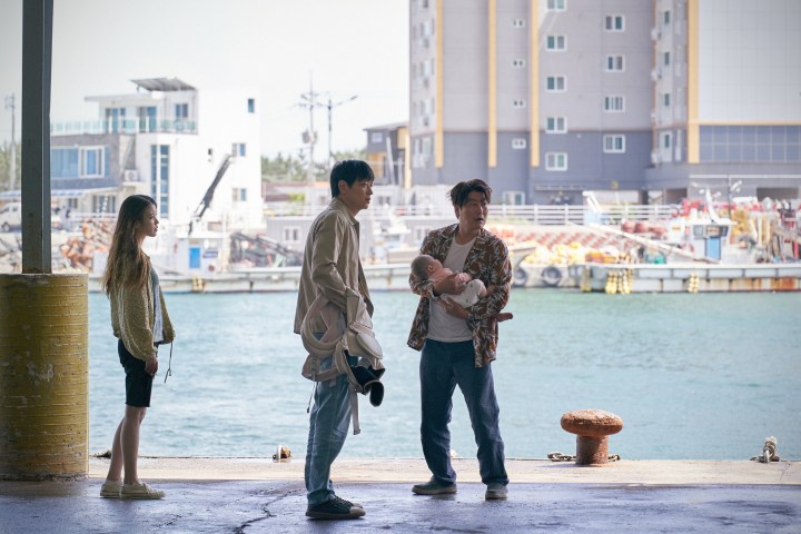 Song Kang-ho, Gang Dong-won, and Lee Ji-eun stand near the sea in Broker.