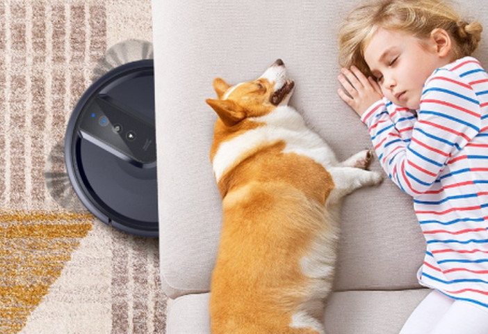 The Anker Eufy 25C Robot Vacuum cleans quietly while a little girl and her dog sleep on the couch.