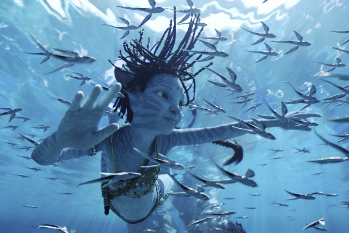 Un niño Na'vi de piel azul nada bajo el agua en una escena de Avatar: The Way of Water.