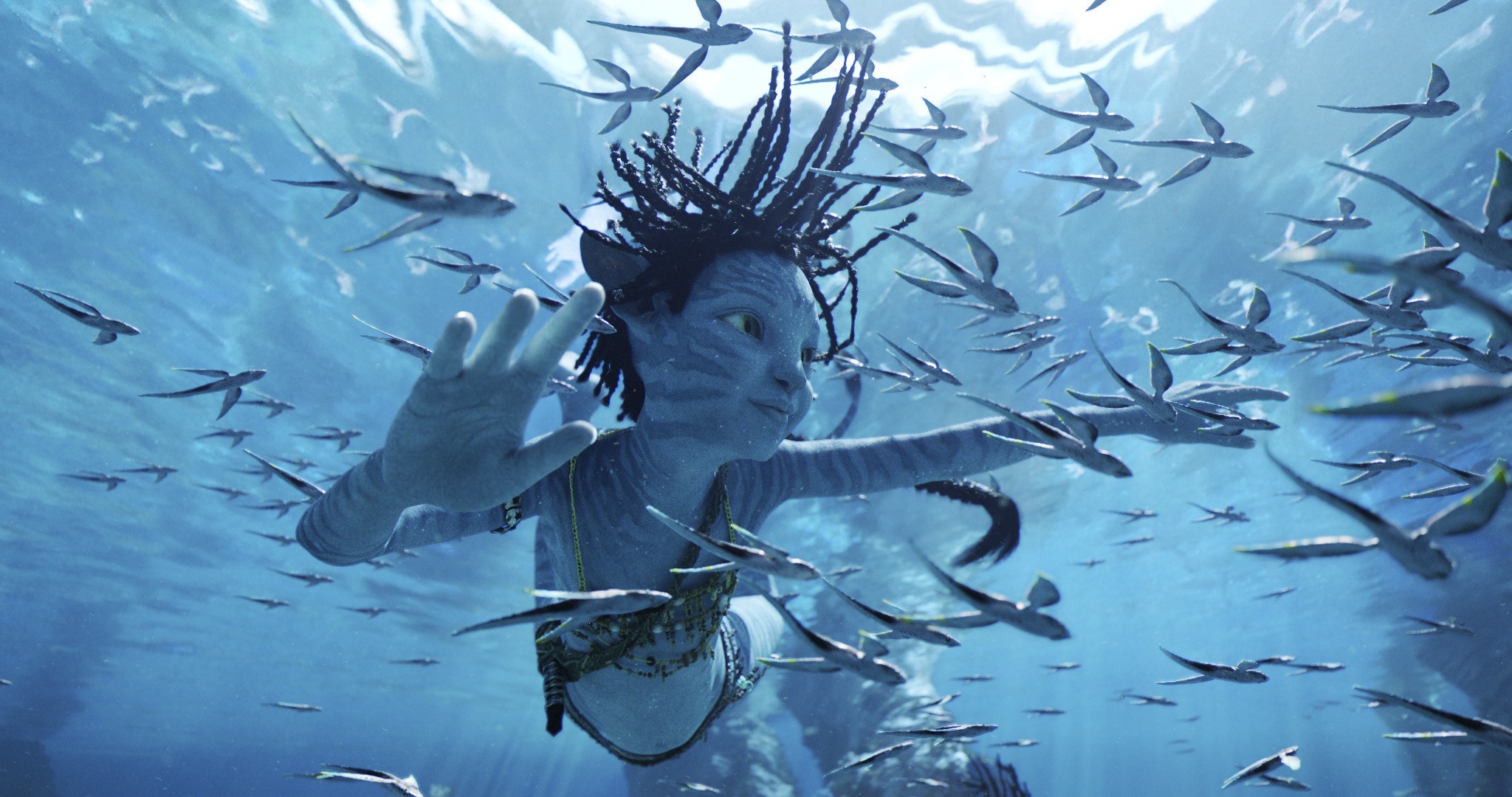 Uma criança Na'vi de pele azul nada debaixo d'água em uma cena de Avatar: The Way of Water.