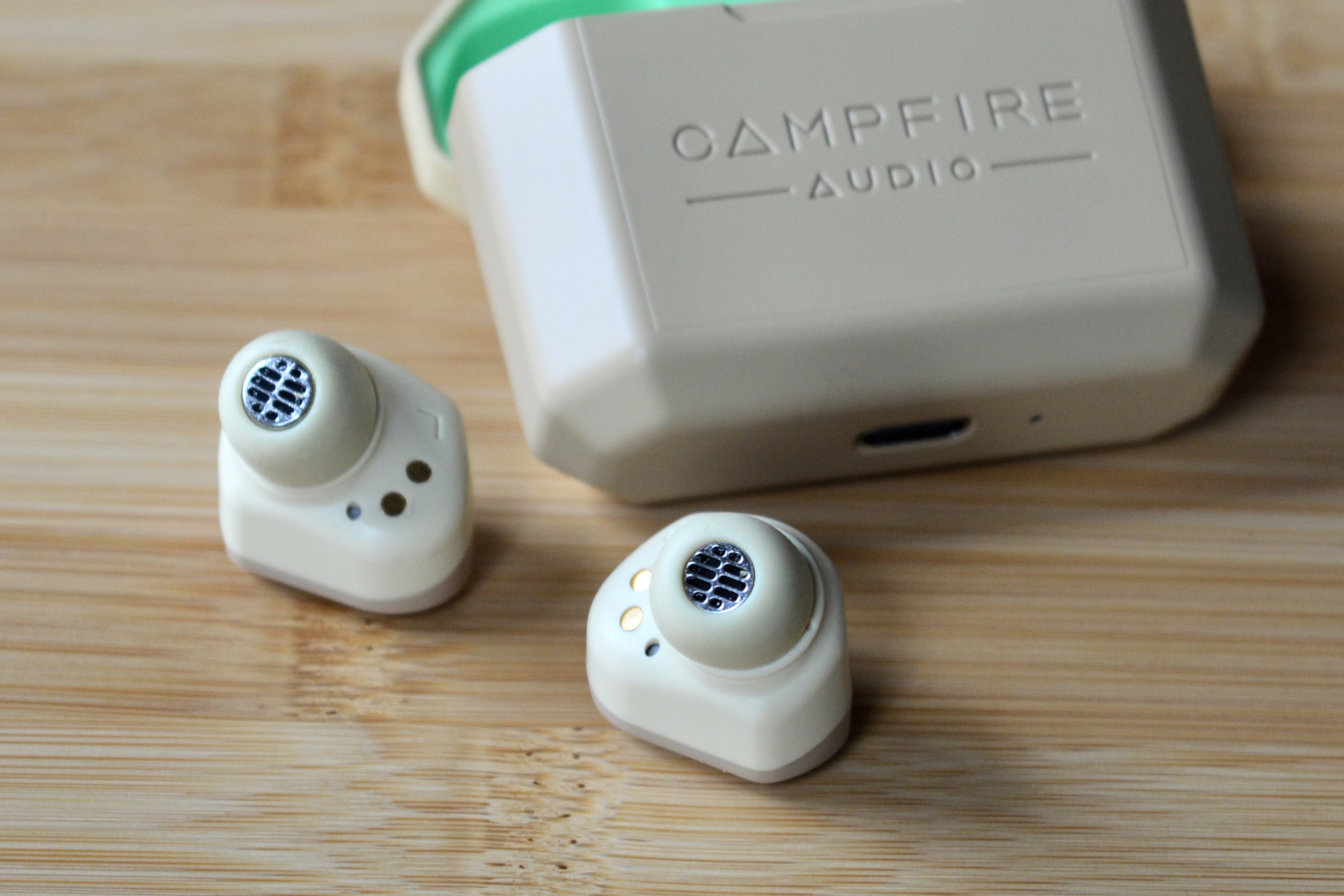 Fones de ouvido Campfire Audio Orbit ao lado do estojo de carregamento.