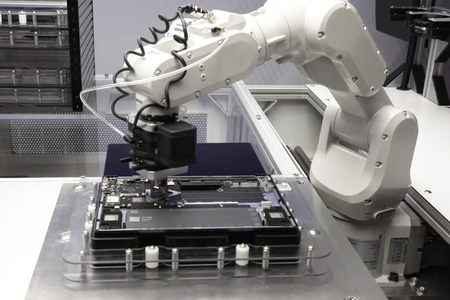 Un brazo robótico extrayendo una placa base de una computadora portátil.