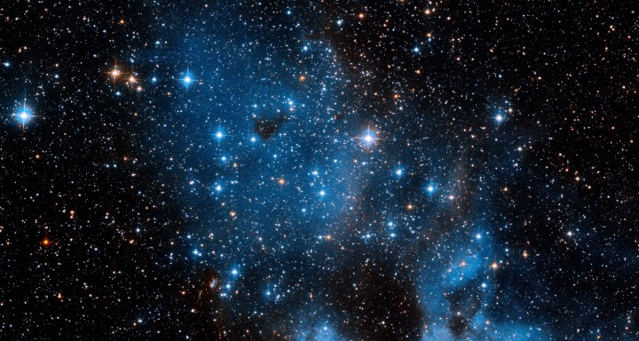 Vor einem mit winzigen Lichtpünktchen übersäten Hintergrund schimmern ein paar hellere Sterne.  Diese ganze Sammlung ist NGC 1858, ein offener Sternhaufen in der nordwestlichen Region der Großen Magellanschen Wolke, einer Satellitengalaxie unserer Milchstraße, die eine Fülle von Sternentstehungsgebieten aufweist.  NGC 1858 wird auf etwa 10 Millionen Jahre geschätzt
