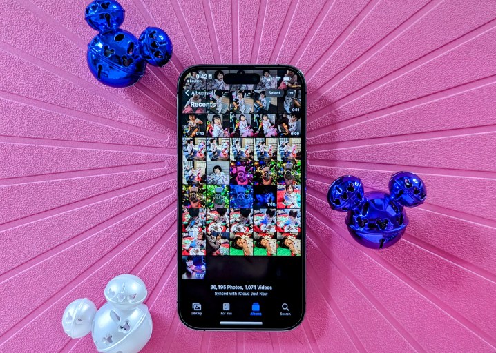 iPhone 14 Pro che mostra il rullino fotografico dell'app Foto con campanellini di Topolino su sfondo rosa