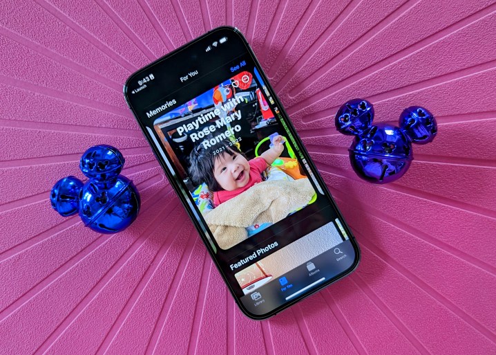 iPhone 14 Pro montrant la fonction Souvenirs de l'application Photos avec des grelots de Mickey sur fond rose