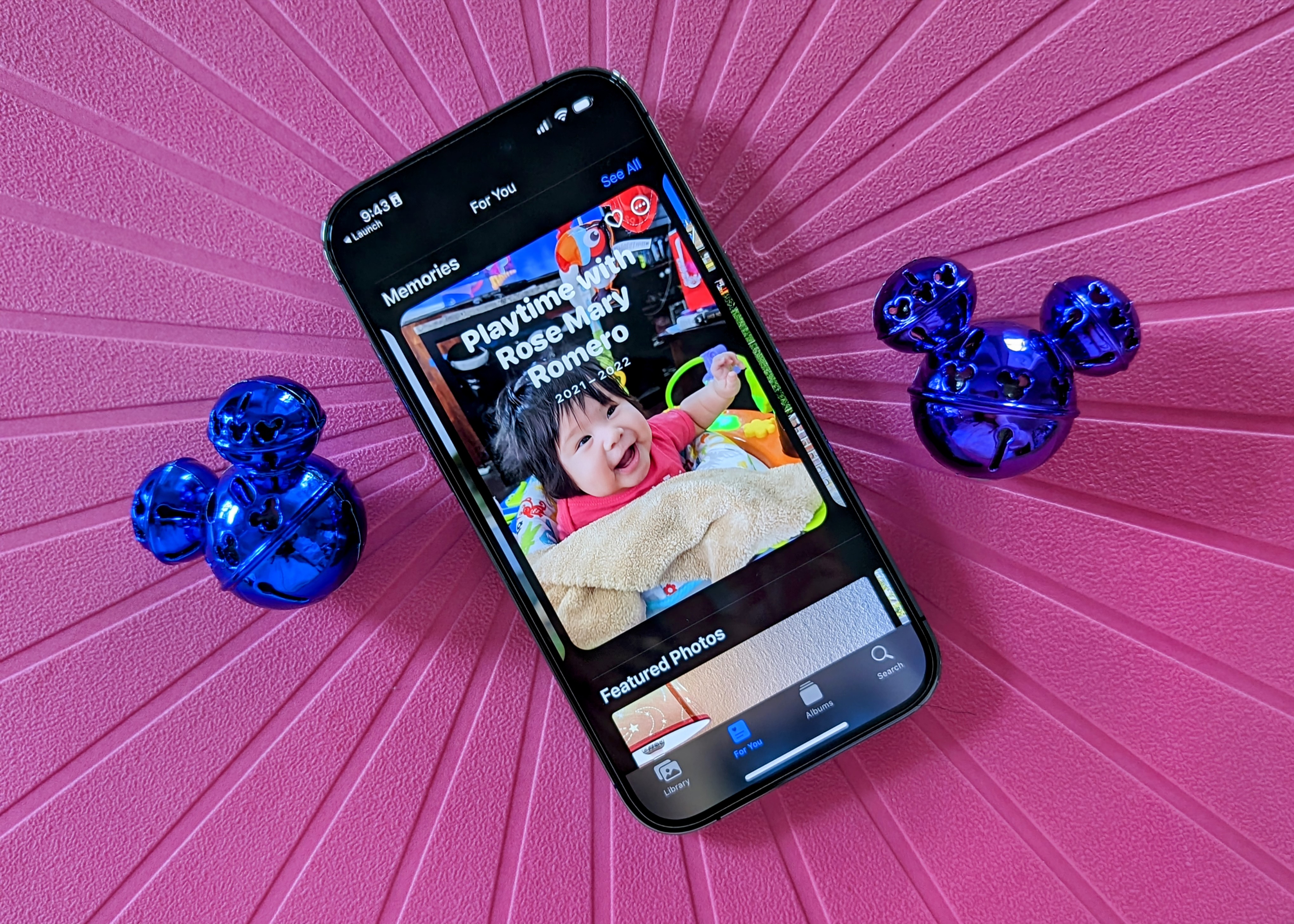 iPhone 14 Pro que muestra la función Recuerdos de la aplicación Fotos con cascabeles de Mickey sobre un fondo rosa