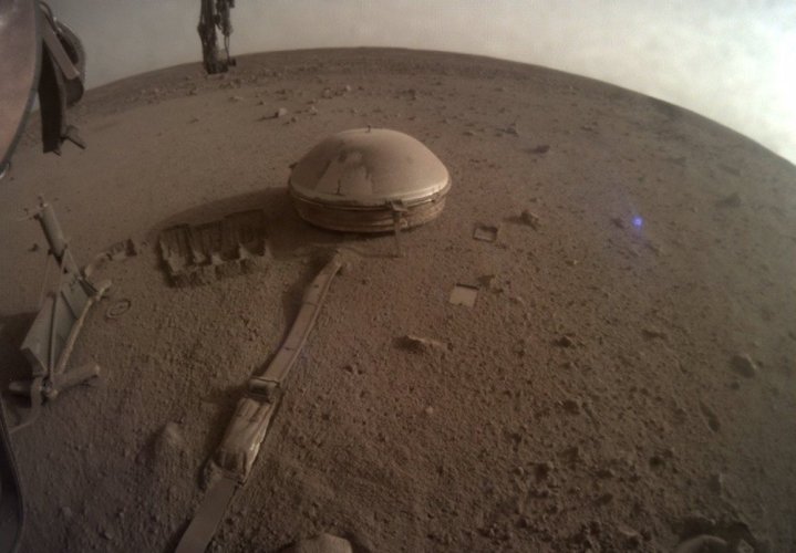 A view from NASA's InSight lander showing its wind and thermal shield covering some of its science instruments.