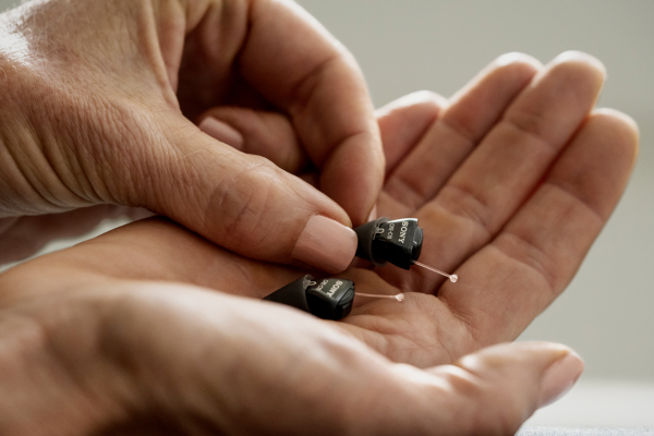 The Sony C10 Self-Fitting OTC Hearing Aids in the palm of a hand.