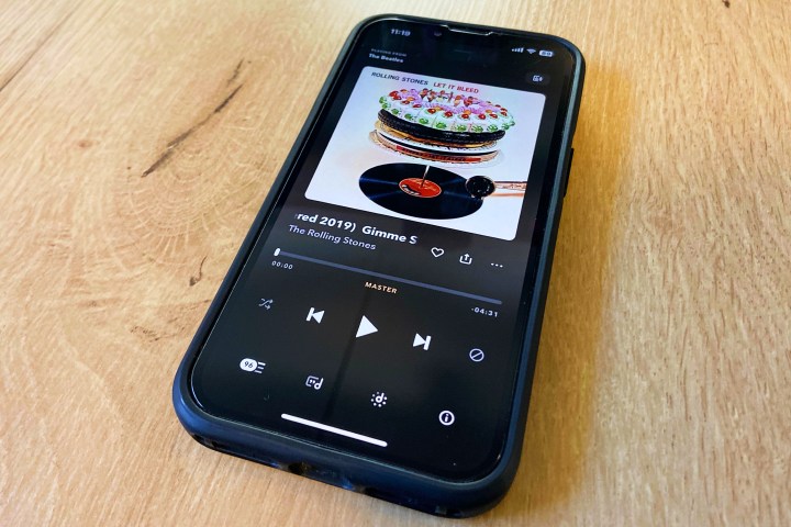 一部 iPhone，在 Tidal 应用程序上播放滚石乐队。