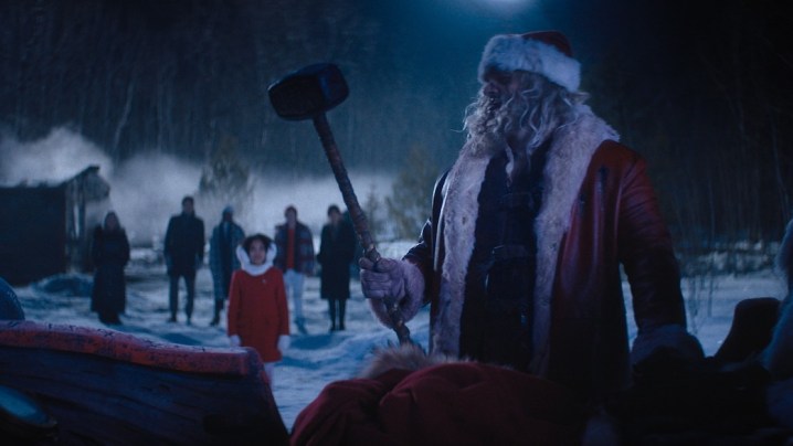 David Harbour, dressed as Santa Claus, lifts a sledgehammer from a sleigh.