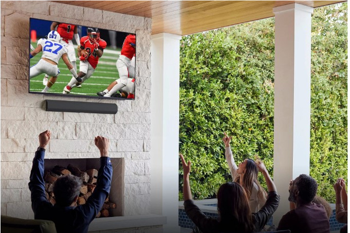 Люди смотрят футбол на настенном 50-дюймовом смарт-телевизоре Vizio Class V-Series.