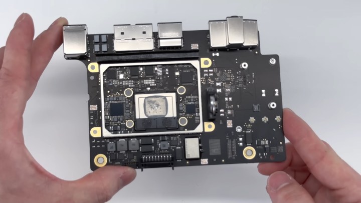 A person holding the logic board of the M2 Mac mini computer from Apple.