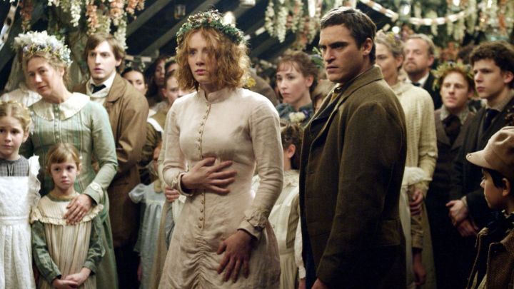A young woman and man among a crowd at a wedding party in the movie The Village.