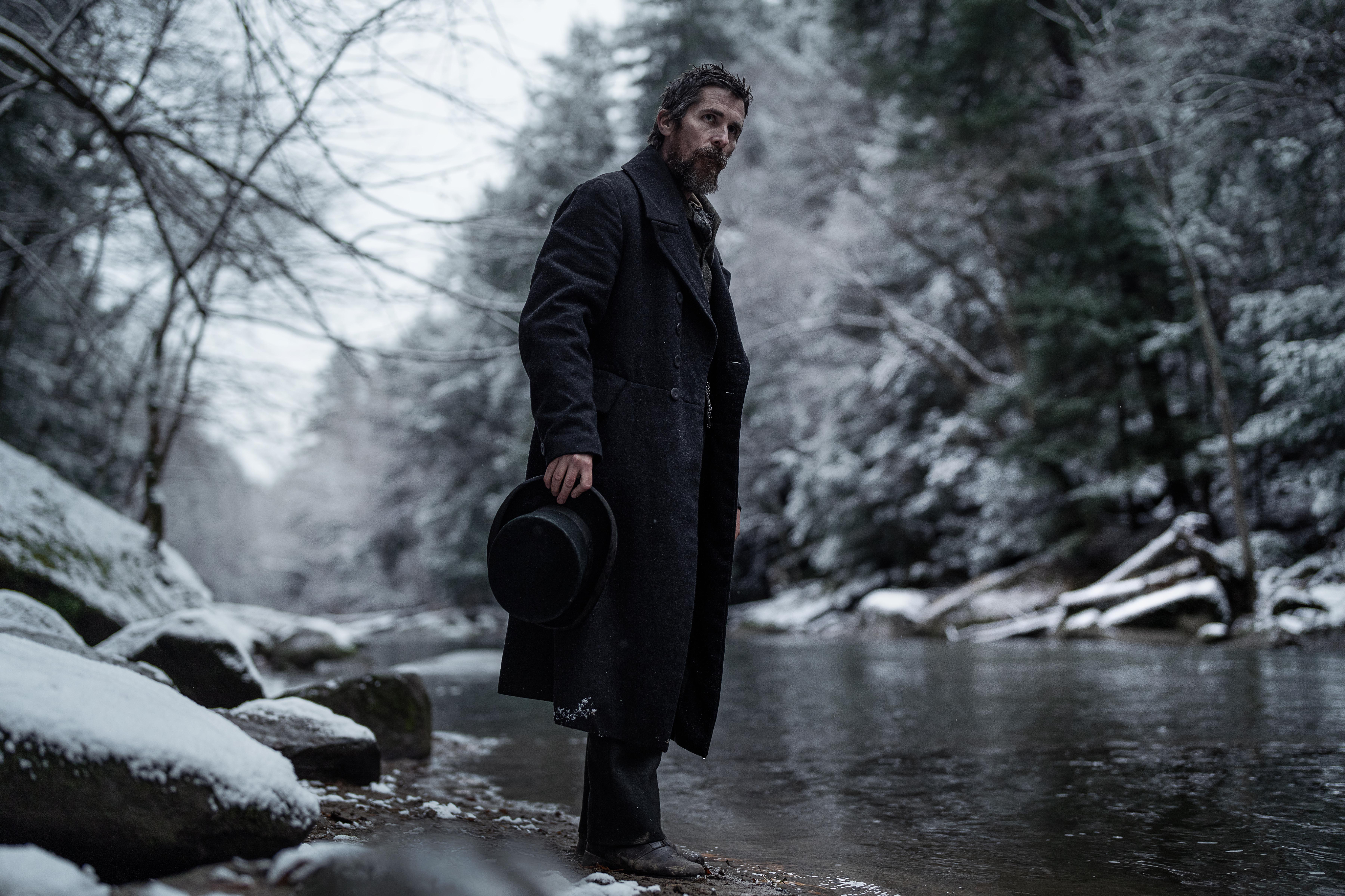 Christian Bale berdiri di dekat sungai di The Pale Blue Eye.