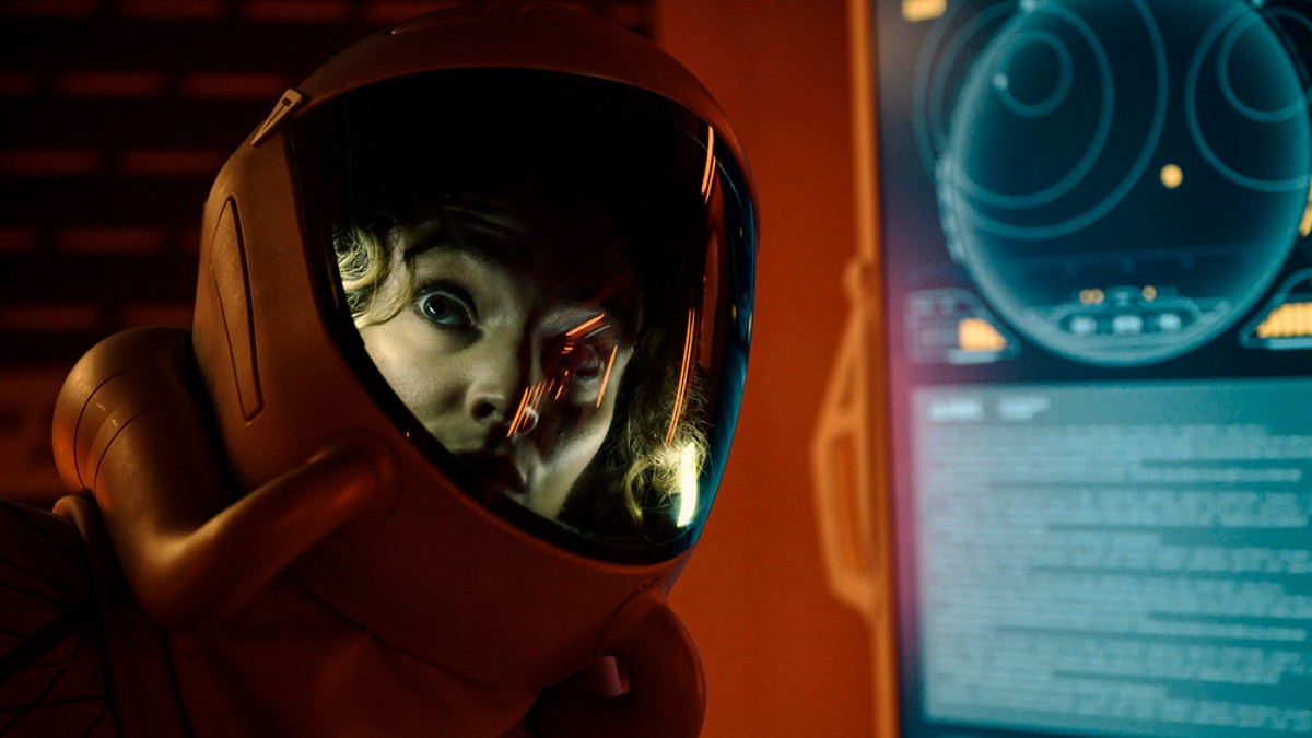 Uma mulher parece assustada em um traje espacial.