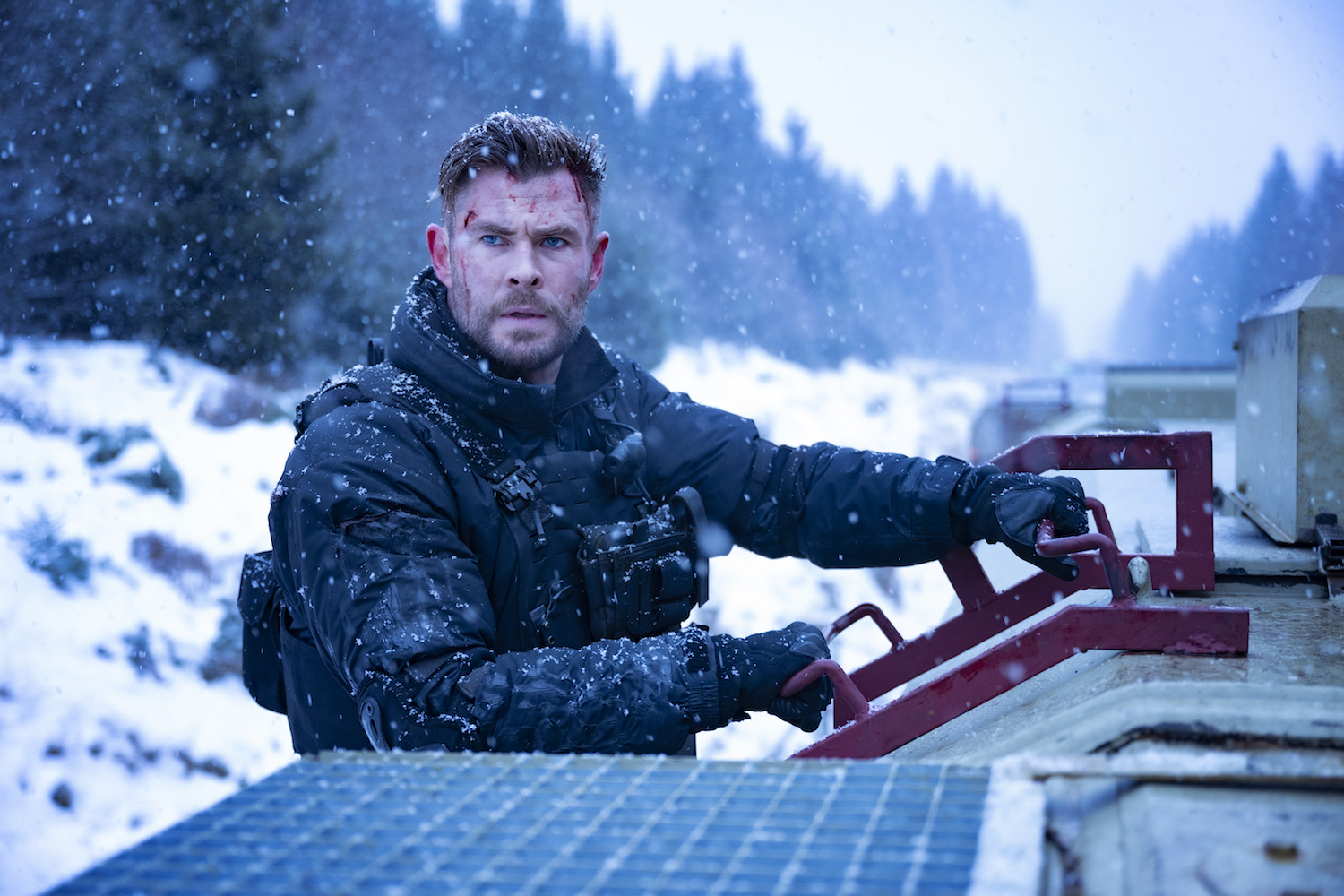Chris Hemsworth segura a placa de um trem em Resgate 2.