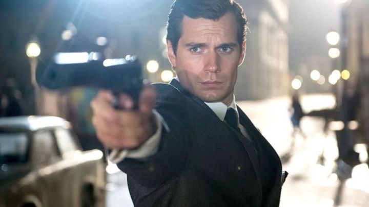 Henry Cavill as Napoleon Solo aiming his gun at something off-camera in The Man from U.N.C.L.E..