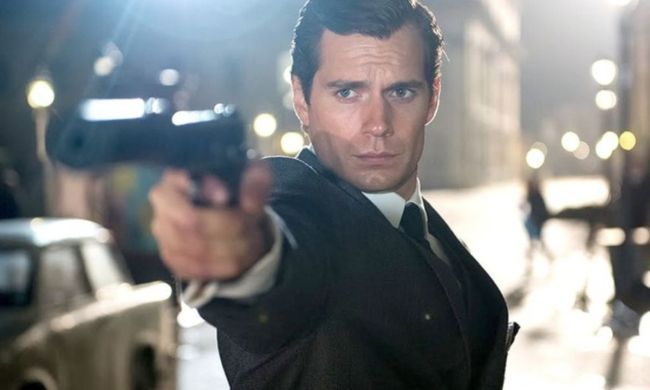 Henry Cavill as Napoleon Solo aiming his gun at something off-camera in The Man from U.N.C.L.E..
