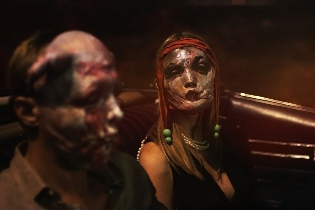 Two people in masks ride in a car in Infinity Pool.