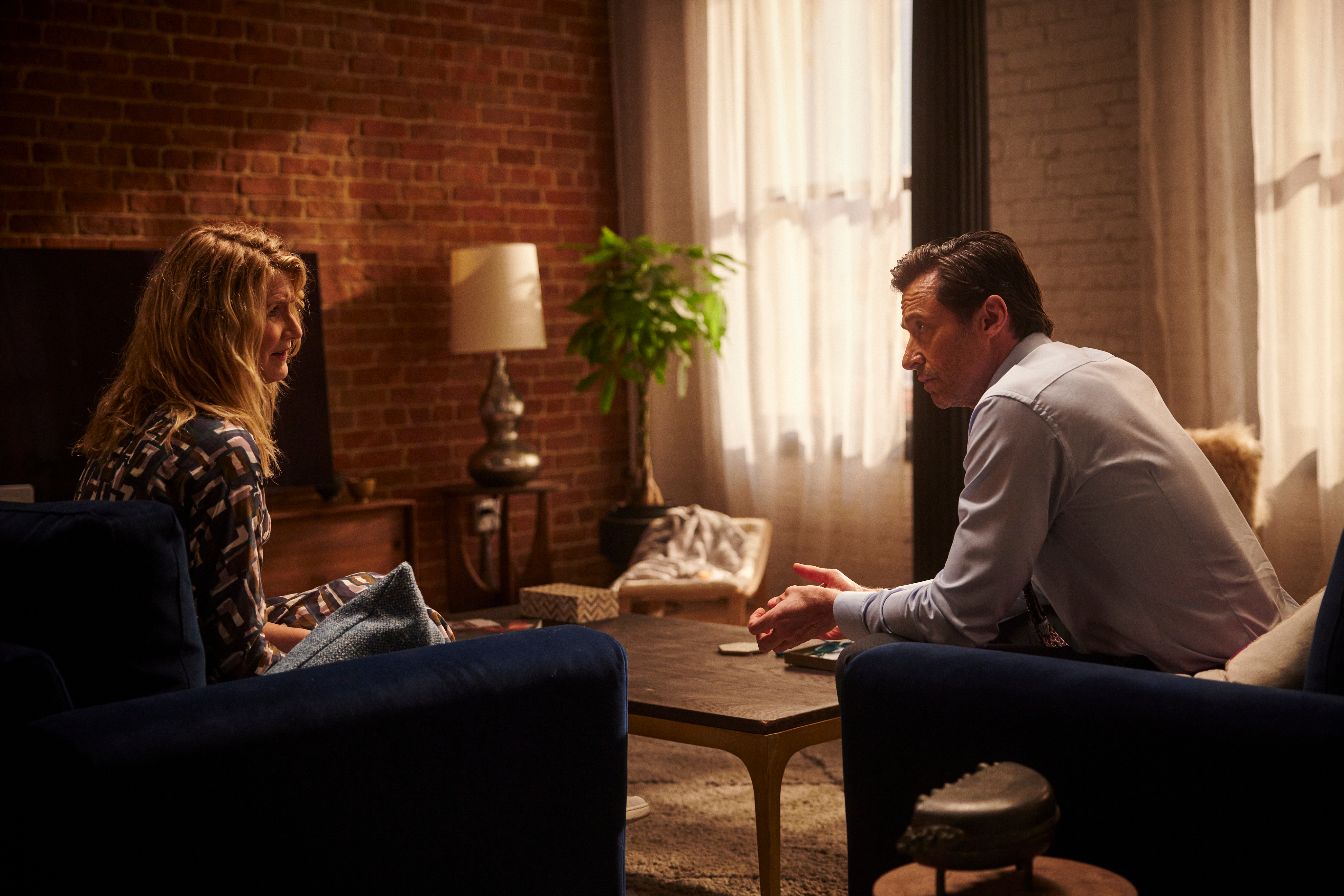 Laura Dern and Hugh Jackman sit near a coffee table together in The Son.