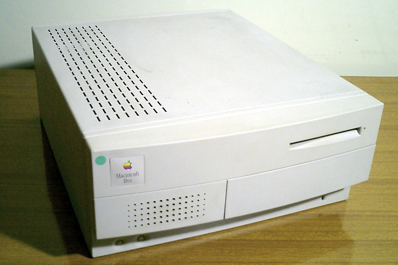 Um computador Apple Macintosh IIvx em uma mesa de madeira.