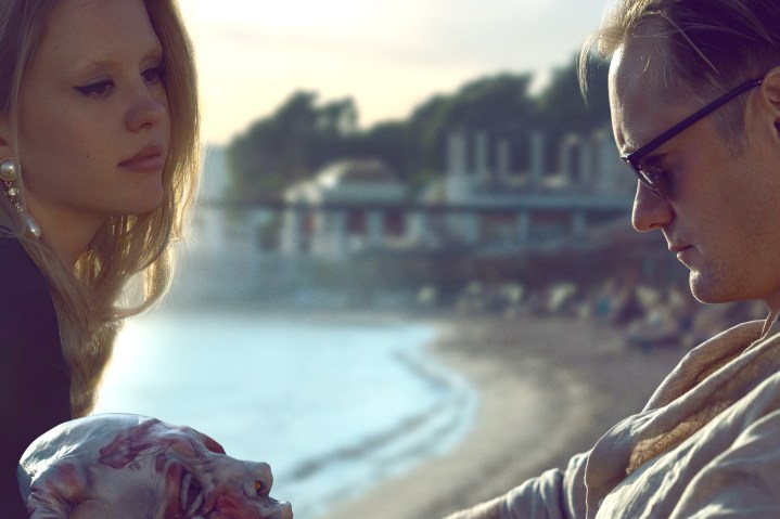 Mia Goth and Alexander Skarsgård sit near a beach together in Infinity Pool.