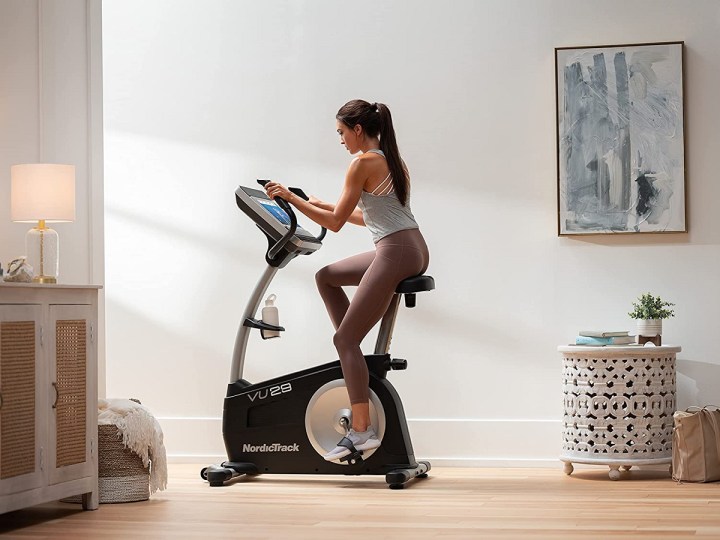 A woman adjusting the settings of the NordicTrack Commercial VU 29 Exercise Bike.