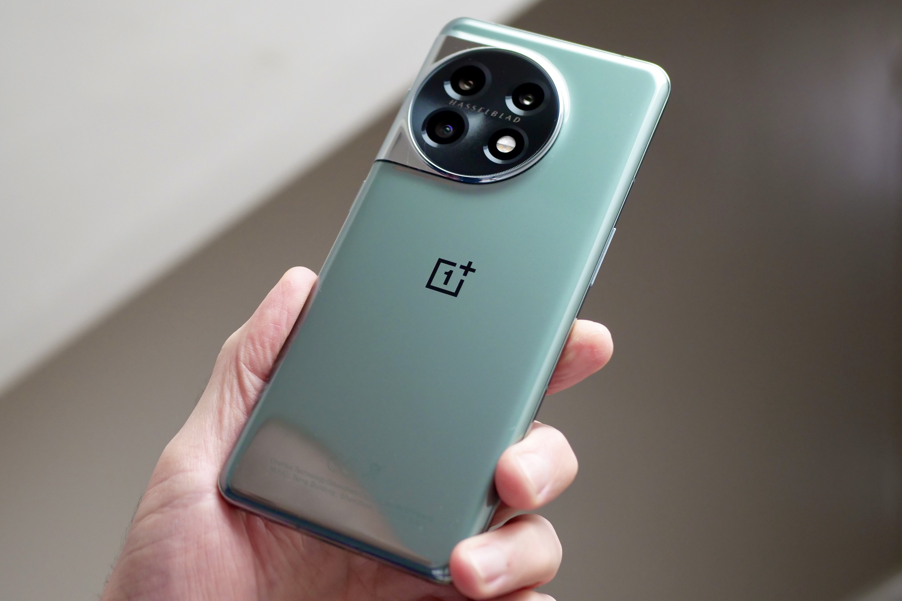 The OnePlus 11 held in a person's hand and seen from the back.