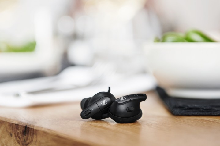 The Sennheiser Conversation Clear Plus earbuds on a table.